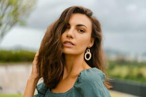 Close  up portrait of elegant brunette woman in trendy crop blouse with puff sleeve posing  in  luxury hotel on the roof top. photo