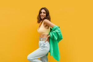 Cheerful pretty girl in stylish summer outfit posing on yelllow background. photo