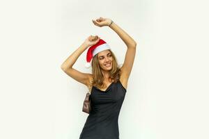 mujer en elegante negro vestir y Papa Noel sombrero bailando y teniendo divertido terminado blanco antecedentes. foto