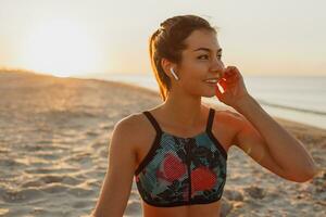 a woman in a sports bra and shorts is doing yoga on the beach photo