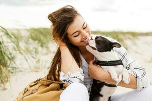 a woman is sitting on the beach with her dog photo