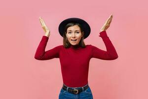 Puzzled  cute  female  spreads hands with doubt, dressed in  red  jumper, isolated over  pink background, blank copy space. Woman faces dilemma, being unsure photo