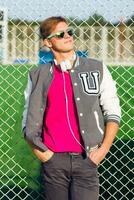 Outdoor fashion portrait of handsome guy in stylish  spring sportive outfit  and posing near sports field. Bright contrast colors. photo