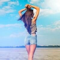 Beautiful slim tanned fitness   girl 's back  with  hands on top. Posing outdoor in stylish jeans shorts. Soft light. photo