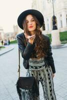 Lifestyle portrait of pretty cheerful woman send kiss, laughing, enjoying  holidays in old European city.  Street fashion  look.   Stylish spring outfit. photo