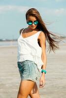 Woman in white t shirt and stylish sunglasses posing on the beach. photo