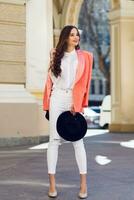 Young  beautiful woman walking in the old city in trendy casual glamour clothes, pink jacket . Spring  or fall season, sunny weather. Full lenght. photo