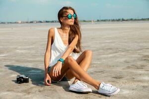 mujer en blanco t camisa y elegante Gafas de sol posando en el playa. foto