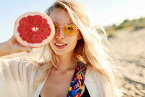 Happy  blonde natural  woman  holding  grapefruit. Healthy diet food. Summer vacation. photo