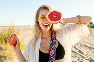 Happy  blonde natural  woman  holding  grapefruit. Healthy diet food. Summer vacation. photo