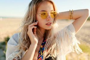 Close up portrait of blonde girl playing with hairs, having fun and enjoying summer on the beach. photo