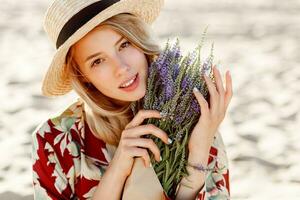 Close up portrait of lovely romantic blond girl enjoying smell of lavender. Skincare concept. photo