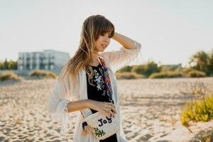 Romantic girl with long hair walking on the beach.   Bohemian style, straw bag , bright make up. photo