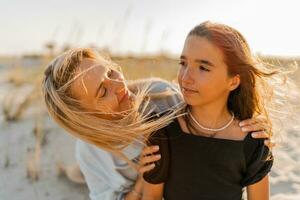 Smiling mother and beautiful daughter have fun on the beach. photo