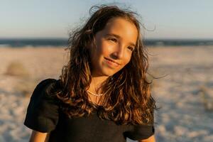 Beautiful brunette  child girl  posing om the beach. Sunset warm colors. photo