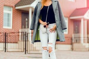Moda detalles de elegante mujer. gris abrigo, blanco pantalones . foto