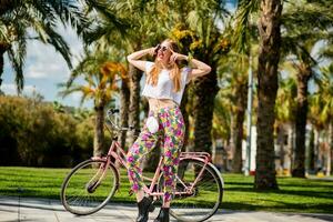 bonito rubio mujer posando al aire libre con bicicleta foto