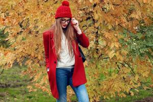 rubia mujer con largo pelos caminando en soleado otoño parque en de moda casual atuendo. foto