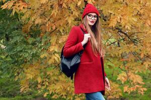 Blonde woman with long hairs walking in sunny  autumn park in trendy casual outfit. photo