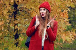 Happy  blonde woman in red hat and jacket posing in autumn park. photo