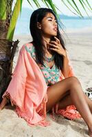 Fashion summer  portrait of young beautiful asian model relaxing on tropical beach. photo