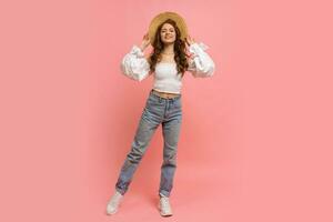 Full lenght image of Ppayful  woman in elegant linen top with balloon sleeves  and blue jeans posing on pink background.  Summer fashion trends. photo
