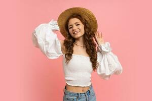 Lovely woman in elegant linen top with balloon sleeves posing on pink background.  Wavy hairs, straw hat, summer fashion trends. photo