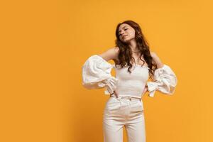Sexy elegant woman in white blouse and trousers posing on yellow background in studdio. Summer fashion trends. photo