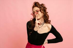 Woman  in suglasses  with suprise face posing over pink background. Wavy hairs. Perfect smile.  Isolate in studio. photo