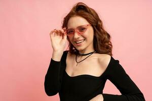 Beautiful red  head woman posing over pink background. Wavy hairs. Perfect smile.  Isolate in studio. photo