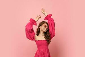 woman dancing  in pink lien dress with  sleeves over pink background. photo