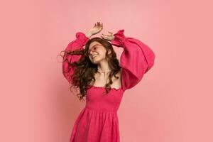 Happy graceful woman dansing  over pink background . Fooling around, having fun. Wearing stylish linen dress. Summer mood. photo