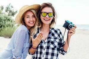 Close up summer lifestyle portrait of two cute women, relaxing near ocean, making photos. photo