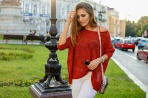 Autumn portrait of blond pretty weoman eith bright make up, orange sweater and white jeans. Walking  outdoor. photo