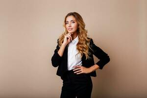 Successful business woman with candid smile and crossed arms in stylish suit   on beige background. photo