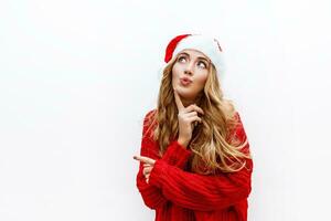 alegre despreocupado rubio mujer en nuevo año sombrero en rojo de punto suéter posando en blanco antecedentes . aislar. Navidad y nuevo año fiesta concepto. foto