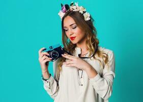 Cute cheerful blonde  fresh  woman with floral wreath on head posing  in spring stylish outfit  taking picture   on bright blue background.Wearing tender floral wreath , spring   clothes. photo