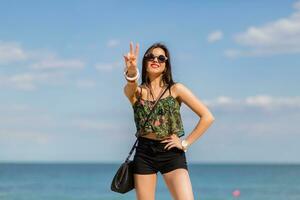 Sexy woman in stylish tropical autfit posing on the beach.  Travel and summer concept. photo