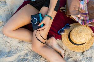 Gorgeous sexy woman with perfect tan body, full red lips and l  long legs posing on the  tropical  sunny beach. Wearing  crop top , shorts and straw hat. Bright sunny colors. photo