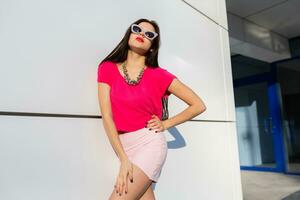 de moda mujer en verano ropa y Gafas de sol posando terminado blanco urbano antecedentes. foto