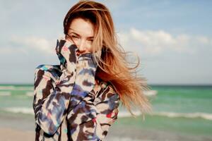 Carefree woman jumping freedom on white sand. Blue ocean background. Windy hairs. photo