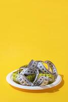 colorful measuring tapes top view on disposable plate on bright yellow background photo