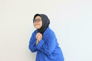 beautiful young Asian Muslim woman, wearing glasses and blue blazer with awe gestures while smiling photo