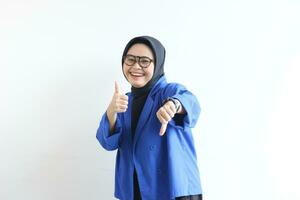 Young beautiful Asian Muslim woman, wearing glasses and blue blazer with angry facial expression photo