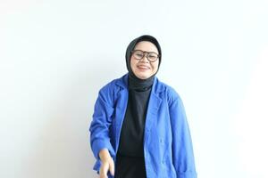 Young beautiful Asian Muslim woman, wearing glasses and blue blazer with happy smiling face expression photo