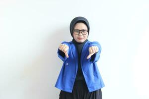 Beautiful young Asian Muslim woman, wearing glasses and blue blazer with hand and face gesturing downplaying something or disappointed photo