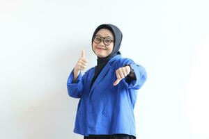 Young beautiful Asian Muslim woman, wearing glasses and blue blazer with angry facial expression photo