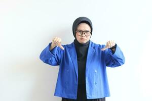 Beautiful young Asian Muslim woman, wearing glasses and blue blazer with hand and face gesturing downplaying something or disappointed photo