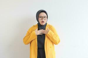 Beautiful young Asian Muslim woman in glasses and smiling putting both hands on chest while shocked expression photo