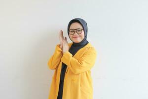 Young beautiful Asian Muslim woman, wearing glasses and yellow blazer with happy smiling face expression photo